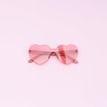 Stylish heart shaped glasses on pink background with copy space