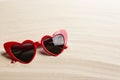 Stylish heart shaped sunglasses on white sand. Summer time
