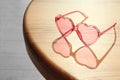 Stylish heart shaped sunglasses on wooden table.