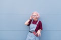 Stylish hipist girl with pink hair stands on the background of a blue wall and listens to music in the headphones Royalty Free Stock Photo