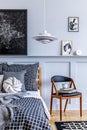 Stylish hipster bedroom interior with design chair, mock up poster frames, book, clock, decoration, carpet, beautiful bed sheets. Royalty Free Stock Photo