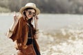 stylish hipster boho woman smiling showing peace sign in sunglasses with hat, leather bag, fringe poncho and accessory. happy Royalty Free Stock Photo