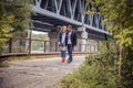 Stylish hipster couple. boho gypsy woman gently hugging arm of confident man under abandoned bridge. atmospheric sensual moment. r