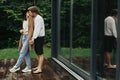 Stylish hipster couple hugging and kissing on wooden terrace, relaxing in cabin in mountains. Happy young family in modern outfits