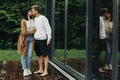 Stylish hipster couple hugging and kissing on wooden terrace, relaxing in cabin in mountains. Happy young family in modern outfits