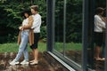 Stylish hipster couple hugging on wooden terrace, relaxing in cabin in mountains. Happy young family in modern outfits embracing