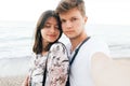 Stylish hipster couple taking selfie on beach at evening sea. Summer vacation. Portrait of happy young family on honeymoon on Royalty Free Stock Photo