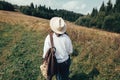 Stylish hipster girl with backpack traveling in sunny mountains. Woman in hat exploring and hiking on top of mountain in sunny Royalty Free Stock Photo