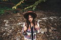 Stylish hipster girl in hat traveling in mountains. Portrait of young beautiful woman with backpack exploring in summer forest. Royalty Free Stock Photo