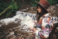 Stylish hipster girl in hat traveling in mountains. Young woman with backpack exploring and looking at map in summer forest. Royalty Free Stock Photo