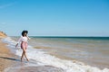 Stylish hipster girl in hat walking on beach and smiling. Summer vacation. Happy young boho woman relaxing and enjoying sunny warm Royalty Free Stock Photo