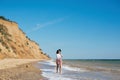 Stylish hipster girl in hat walking on beach and smiling. Summer vacation. Happy young boho woman relaxing and enjoying sunny warm Royalty Free Stock Photo