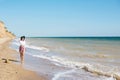 Stylish hipster girl in hat walking on beach and smiling. Summer vacation. Happy young boho woman relaxing and enjoying sunny warm Royalty Free Stock Photo