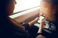 stylish hipster girl holding phone with headphones at window light in train. beautiful young woman looking at smartphone empty sc Royalty Free Stock Photo