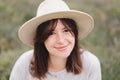 Stylish hipster girl in linen dress and hat sitting on bench at lavender field and relaxing in the morning. Portrait of bohemian