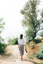 Stylish hipster girl relaxing on beach.  Happy young boho woman in white shirt walking barefoot on tropical island at sandy cliff Royalty Free Stock Photo