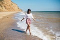 Stylish hipster girl relaxing on beach and having fun.  Happy young boho woman walking and smiling in sea waves in sunny warm day Royalty Free Stock Photo
