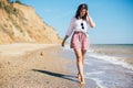 Stylish hipster girl relaxing on beach and having fun.  Happy young boho woman walking and smiling in sea waves in sunny warm day Royalty Free Stock Photo