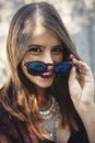 Stylish hipster girl smiling in sunny street on background of wooden wall. Portrait of boho girl in cool outfit and sunglasses Royalty Free Stock Photo