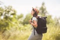 Stylish hipster girl in straw hat traveling countryside. Young woman with backpack exploring and walking in summer nature park. Royalty Free Stock Photo