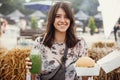Stylish hipster girl in sunglasses holding delicious vegan burger and smoothie in glass jar in hands at street food festival.