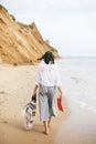 Stylish hipster girl walking barefoot on beach, holding bag and shoes in hand. Summer vacation. Space for text. Calm moment. Happy Royalty Free Stock Photo