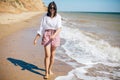 Stylish hipster girl  walking on beach and smiling. Summer vacation. Happy young boho woman relaxing and enjoying sunny warm day Royalty Free Stock Photo