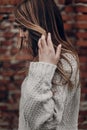 stylish hipster gypsy woman posing in knitted sweater on background of brick wall. atmospheric windy sensual moment. boho country Royalty Free Stock Photo