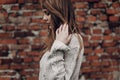 stylish hipster gypsy woman posing in knitted sweater on background of brick wall. atmospheric windy sensual moment. boho country Royalty Free Stock Photo