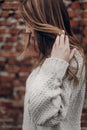 stylish hipster gypsy woman posing in knitted sweater on background of brick wall, holding hair. atmospheric sensual moment. Royalty Free Stock Photo