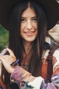 stylish hipster,happy woman in hat holding apatura iris on fingers in forest in mountains. beautiful butterfly on girl hand.