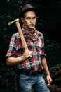 stylish hipster lumberjack with ax in the sunny forest in mountains Royalty Free Stock Photo