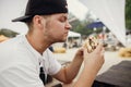 Stylish hipster man eating delicious vegan burger at street food festival. Hungry man biting burger with vegetables in summer