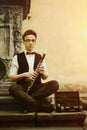 Stylish hipster man playing clarinet on background of old city s Royalty Free Stock Photo