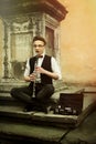 Stylish hipster man playing clarinet on background of old city s Royalty Free Stock Photo