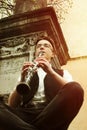 Stylish hipster sitting man playing clarinet on background of o Royalty Free Stock Photo