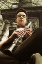 Stylish hipster sitting man playing clarinet on background of o Royalty Free Stock Photo