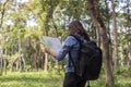 Stylish hipster traveler exploring map at sunny forest and lake in the mountains landscape