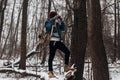 Stylish hipster traveler holding camera and making photo in snow