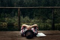 Stylish hipster traveler playing harmonica at sunny lake in the