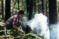 Stylish hipster traveler starting fire in sunny forest in the mo Royalty Free Stock Photo