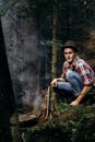 Stylish hipster traveler starting fire in sunny forest in the mo Royalty Free Stock Photo