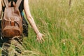 Stylish hipster traveler walking in grass and holding in hand h