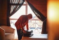 Stylish hipster traveller man in red hat in wooden house packing suitcase