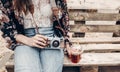 stylish hipster woman holding lemonade and old photo camera. boho girl in denim and bohemian clothes, holding cocktail sitting on