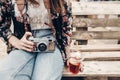 stylish hipster woman holding lemonade and old photo camera. boho girl in denim and bohemian clothes, holding cocktail sitting on