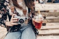 stylish hipster woman holding lemonade and old photo camera. boho girl in denim and bohemian clothes, holding cocktail sitting on