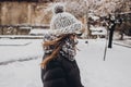 stylish hipster woman in knitted hat standing in snowy city street. beautiful fashionable girl in warm clothes in cold weather wi Royalty Free Stock Photo