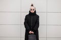 Stylish hipster young woman in stylish sunglasses in a bandana in a fashionable long jacket with a leather stylish backpack Royalty Free Stock Photo