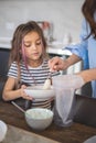 Mom and daughter prepare icing for gingerbread in their home kitchen. Beat with a blender. The girl helps the woman. Royalty Free Stock Photo